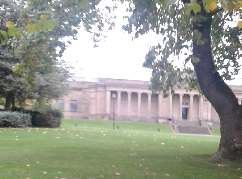 blurry photo of Old Entrance to Sheffield Museum through trees in Winston Park