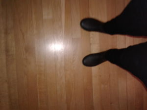 Legs and feet all black on light wood floor. Waiting for a job interview staff diversity. 